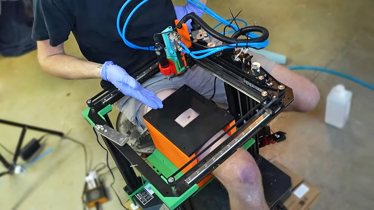 A guy's leg encased in a 3D printer showing a fresh printed tattoo