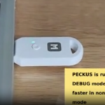 A USB dongle is shown connected to a laptop computer. A text box in the lower right corner says "PECKUS is running in DEBUG mode, it is 3x faster in non-DEBUG mode."