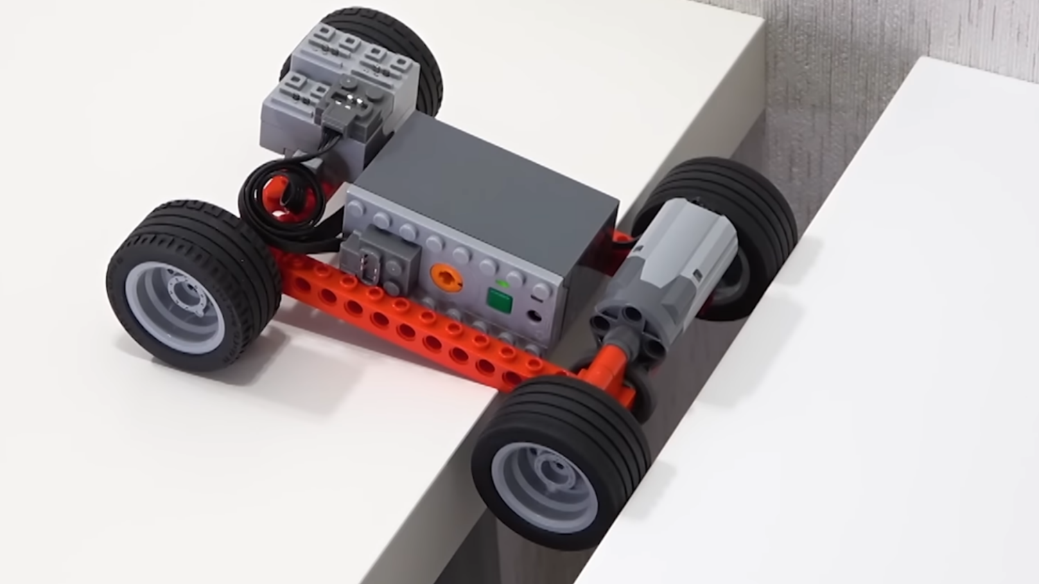 A Lego vehicle crossing a gap between two benches.
